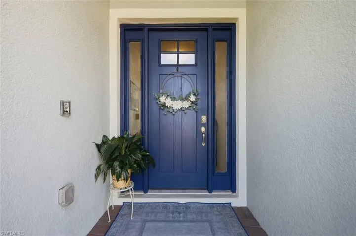 Navy blue front door featuring a glass-paneled upper window, flanked by two full-length sidelights, and equipped with metal hardware