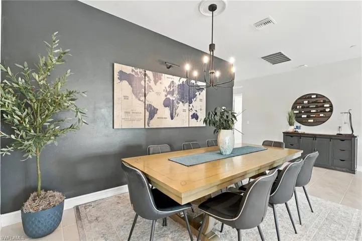 Spacious and inviting dining area featuring a dark charcoal accent wall, multi-light metal chandelier, and large-format neutral tile flooring