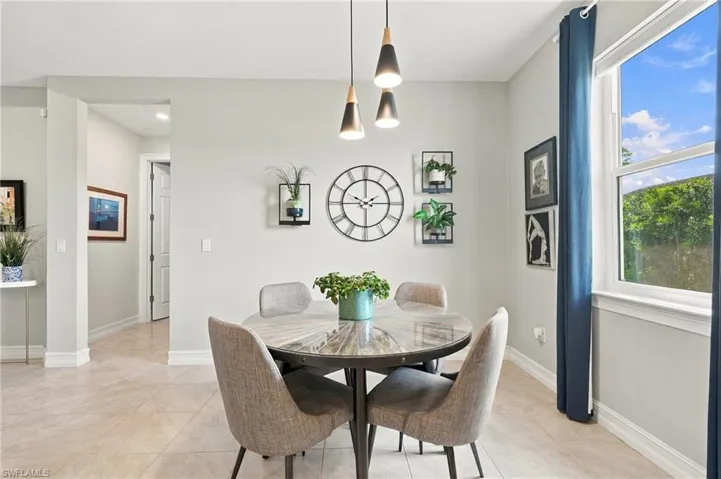 Neutral-toned interior space featuring large-format tile flooring, a tiered three-light matte black pendant fixture, and a single-hung window