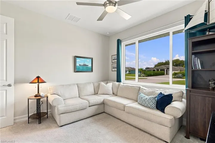 Bright and inviting fourth bedroom is being used as a den and features large multi-pane window at the front of the house and a ceiling fan with integrated lighting