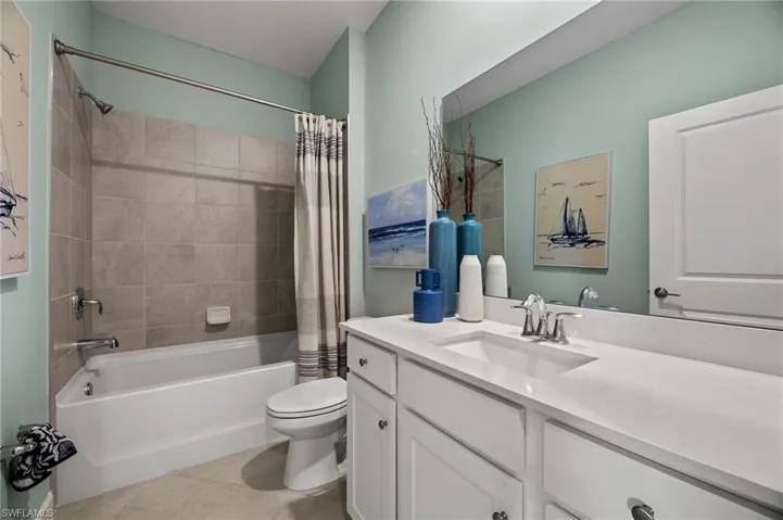Bathroom with vanity, shower / bath combo with shower curtain, and tile patterned flooring