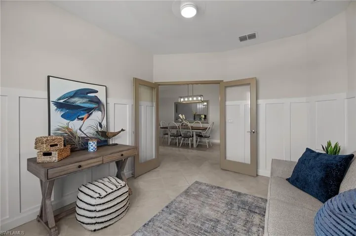 Living room featuring a decorative wall, a wainscoted wall, and light tile patterned floors