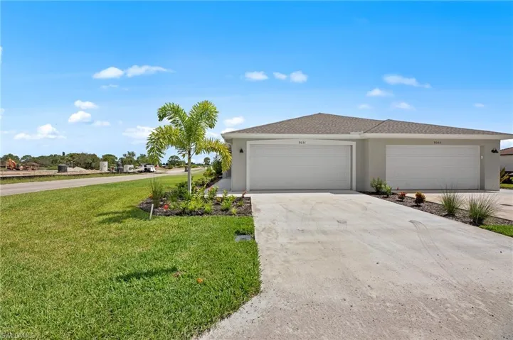 View of front of house featuring stucco siding, driveway, a front yard, and a garage