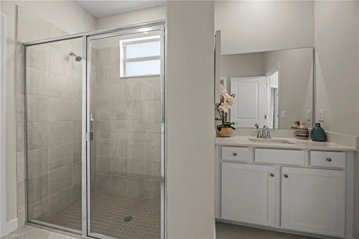 Bathroom with a shower stall, vanity, and tile patterned flooring