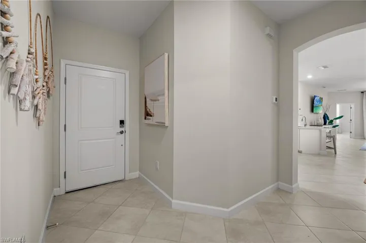 Hallway featuring arched walkways, light tile patterned floors, and recessed lighting