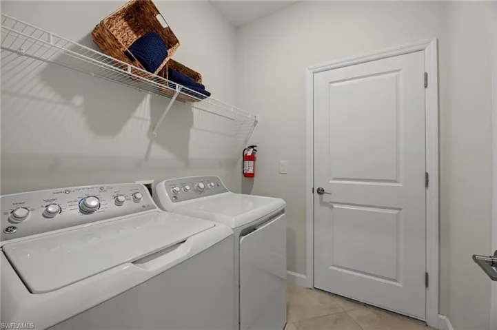 Laundry room with separate washer and dryer and light tile patterned flooring