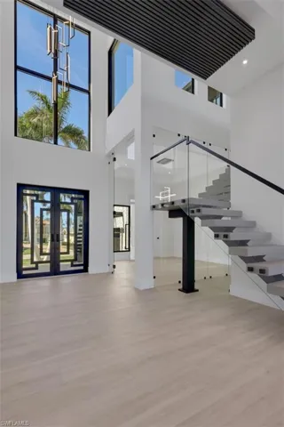 Foyer, floating stairs and double 12' high glass doors to den or formal dining room