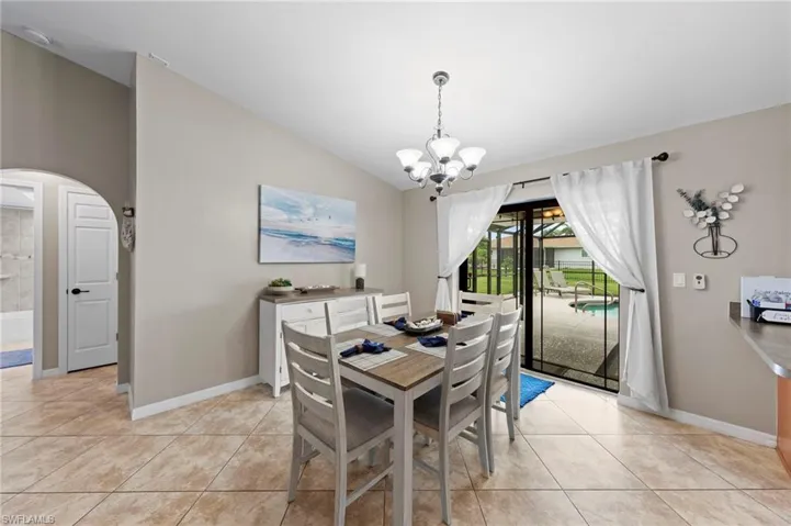 Dining space featuring a chandelier, light tile patterned floors, arched walkways, and lofted ceiling