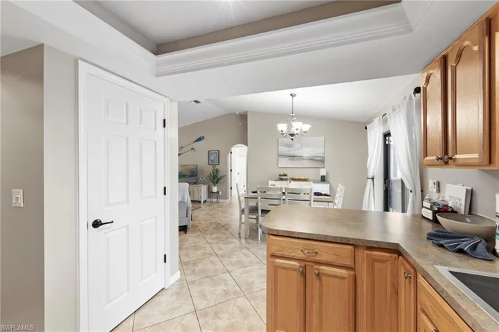 Kitchen featuring arched walkways, a peninsula, light tile patterned floors, a chandelier, and vaulted ceiling