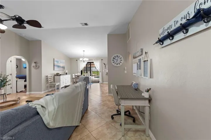 Living area featuring a chandelier, ceiling fan, arched walkways, and light tile patterned flooring