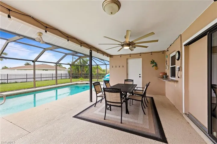 View of swimming pool with a patio, ceiling fan, glass enclosure, and outdoor dining area