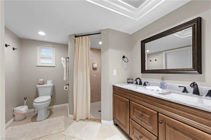 Bathroom featuring a tile shower, double vanity, and tile patterned floors