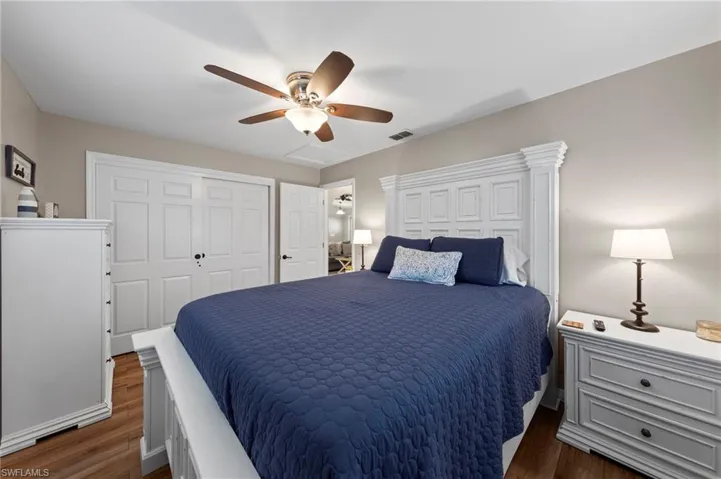 Bedroom with dark wood-style flooring, ceiling fan, and a closet