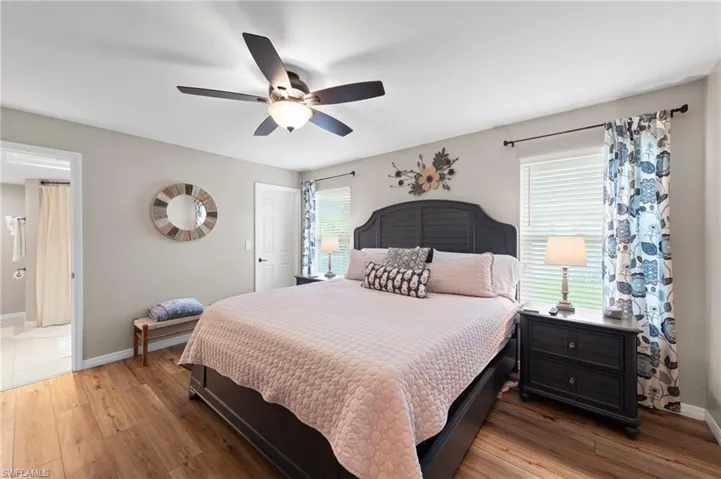 Bedroom with wood-type flooring, ceiling fan, and ensuite bath