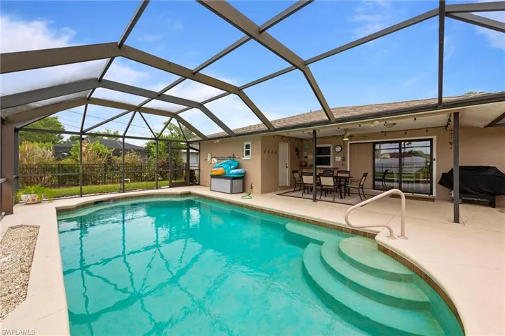 Swimming pool with a patio area, a grill, and glass enclosure