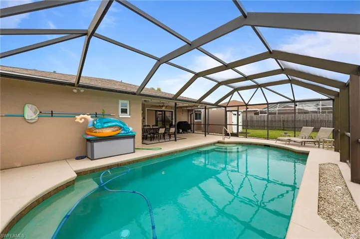 View of swimming pool with a patio area, ceiling fan, and glass enclosure