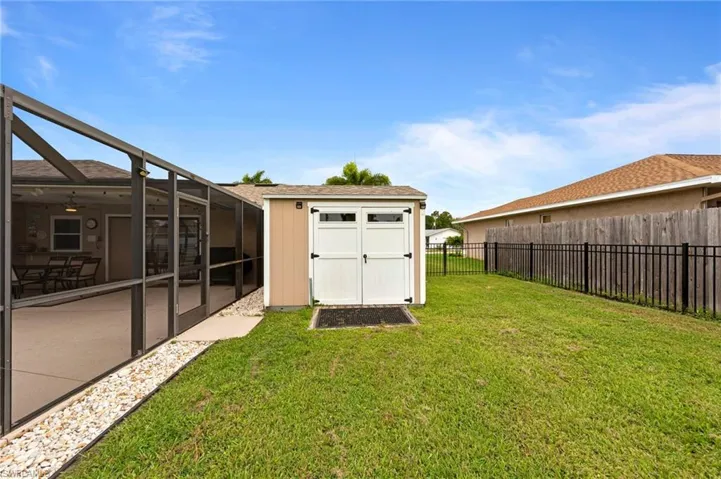 Fenced backyard featuring a shed and a lanai