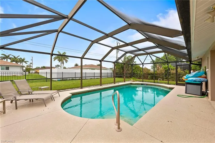 View of pool featuring a patio area, a fenced backyard, and glass enclosure