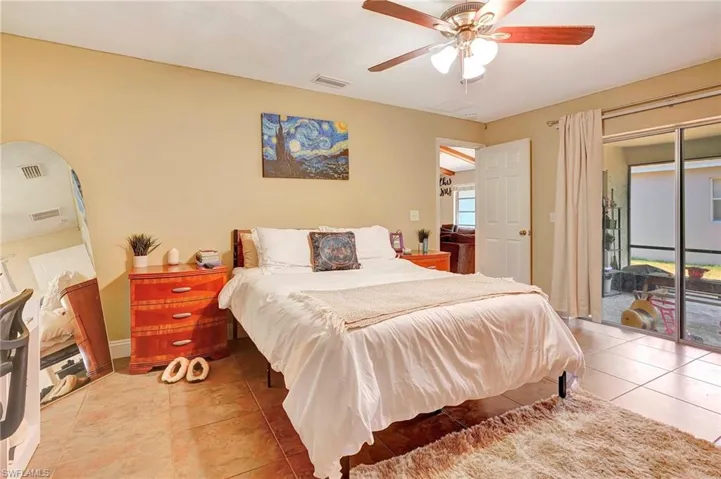 Tiled bedroom featuring ceiling fan and access to outside