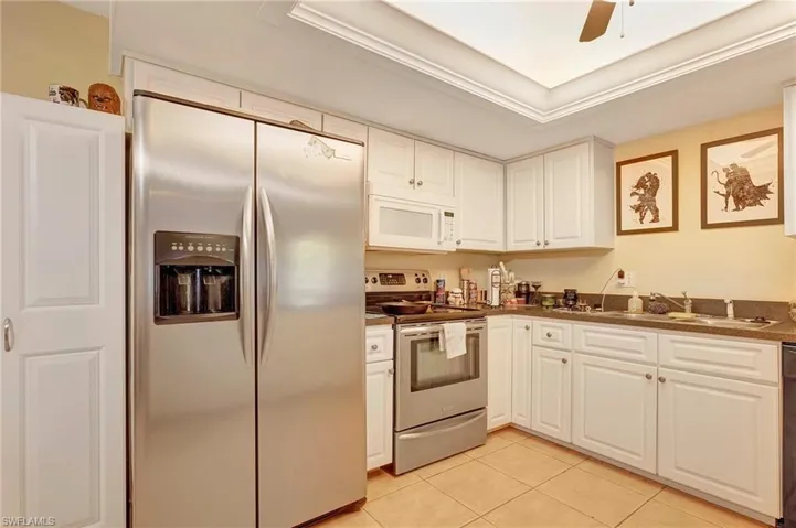 Kitchen featuring ceiling fan, white cabinets, light tile floors, and appliances with stainless steel finishes