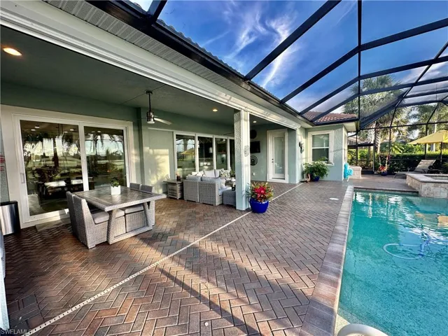 View of pool featuring a lanai, a patio, outdoor lounge area, and a jacuzzi