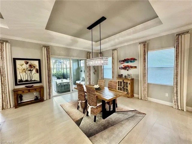 Dining space with an inviting chandelier, a tray ceiling, and crown molding