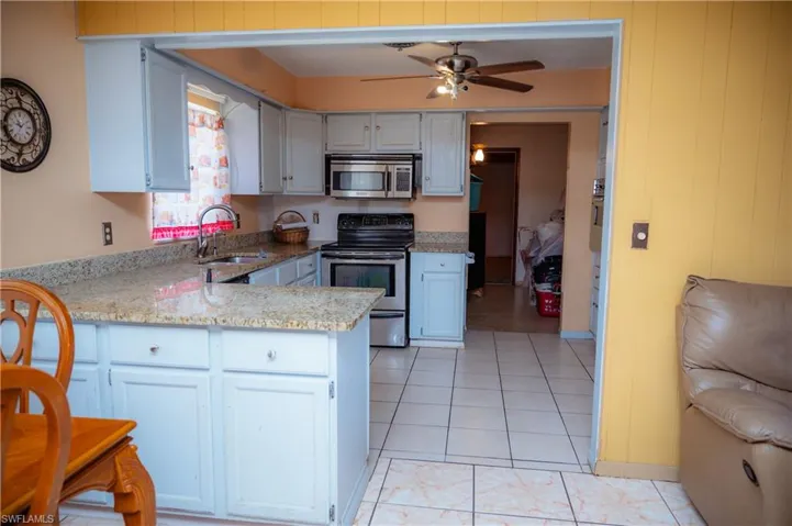 Kitchen featuring light-toned cabinetry, granite countertops, tile flooring, and stainless steel appliances