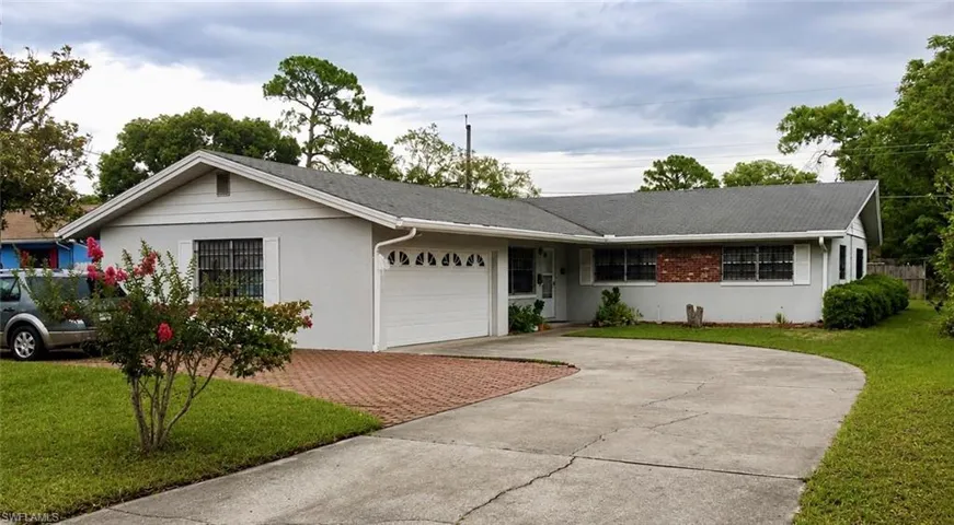 Exterior featuring a two-car garage, partial brick facade, and a combination concrete and paver driveway