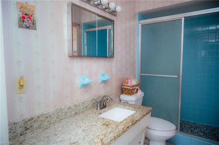 Bathroom featuring a vanity with an integrated sink, a granite-patterned countertop, and a chrome faucet