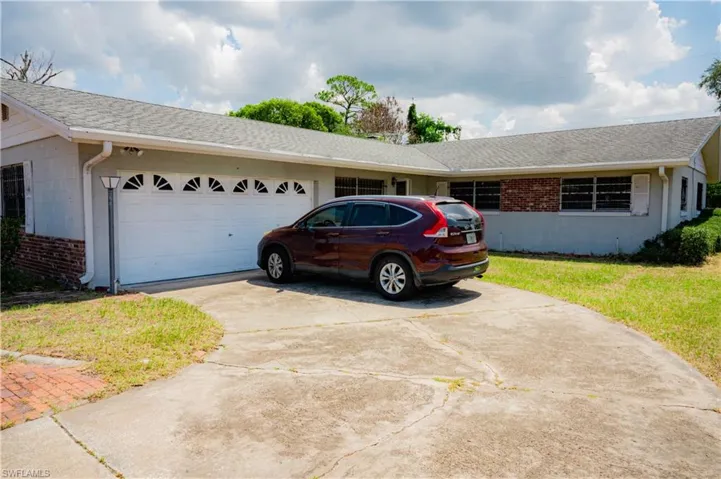 Spacious concrete driveway leading to an attached two-car garage with decorative windows