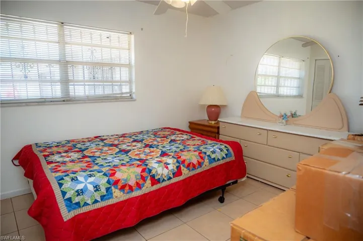 Bedroom featuring a window with horizontal blinds, tiled flooring, and a ceiling fan