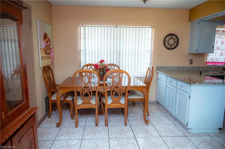 Dining area featuring a window with vertical blinds, light-toned wall paint, and white square tile flooring