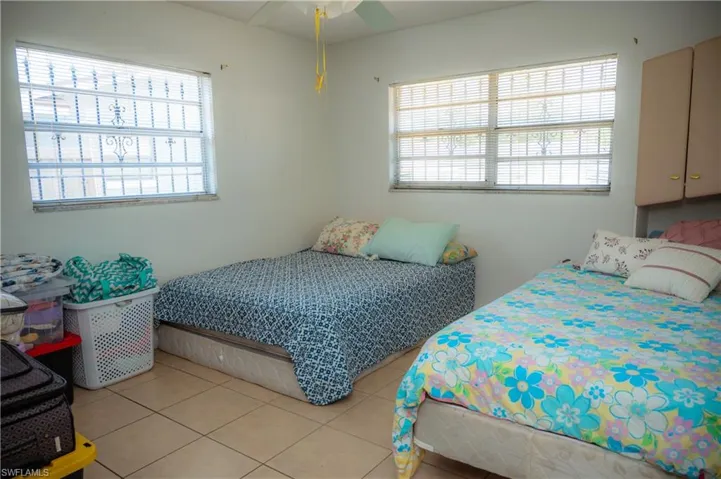 White-painted room featuring two windows with horizontal blinds and decorative security bars