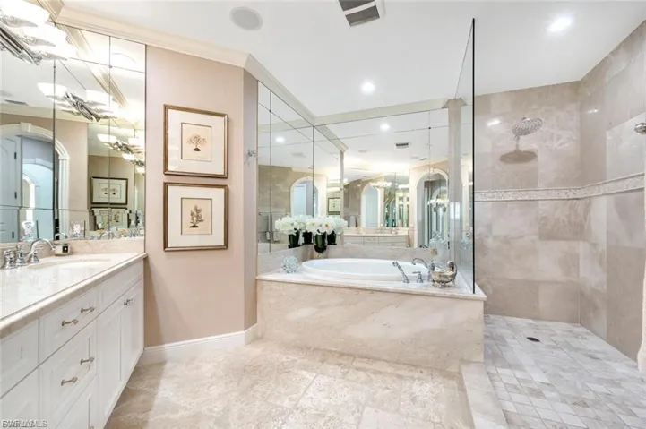 Full bath with a walk in shower, vanity, a garden tub, and crown molding