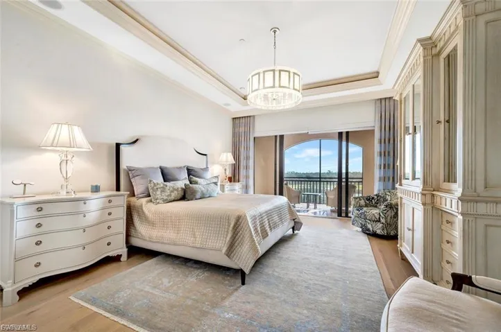 Bedroom with a raised ceiling, light wood-style flooring, access to outside, crown molding, and suspended lighting