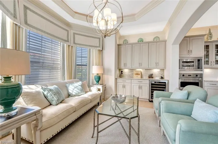 Sitting room with beverage cooler, suspended lighting, ornamental molding, and light wood-type flooring