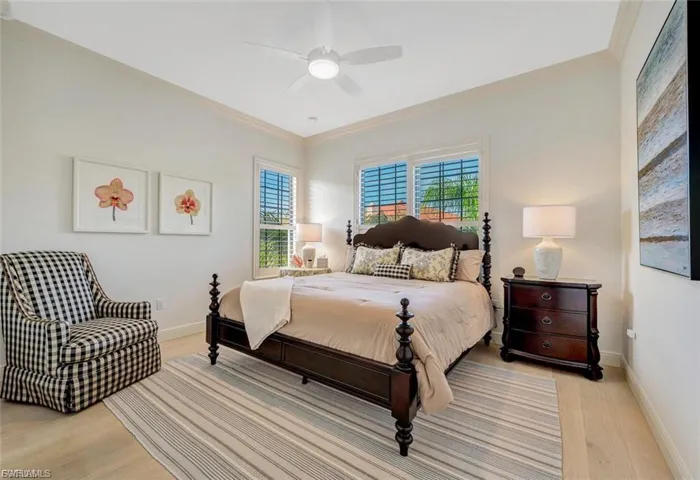 Bedroom with ornamental molding, light wood-style floors, multiple windows, and a ceiling fan