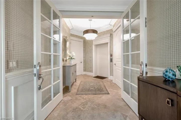 Entryway featuring wallpapered walls, ornamental molding, french doors, and elevator