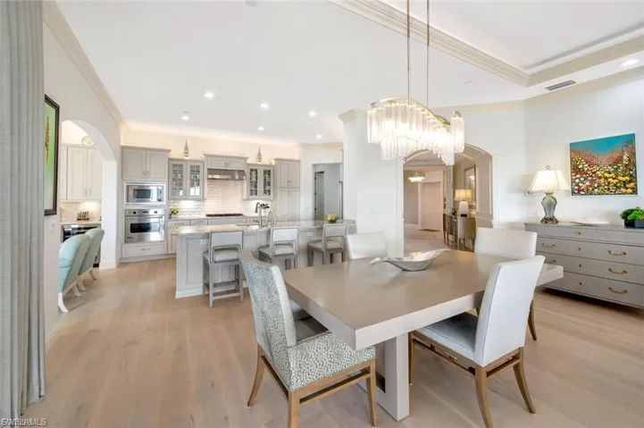 Dining room with arched walkways, crown molding, light wood finished floors, and recessed lighting
