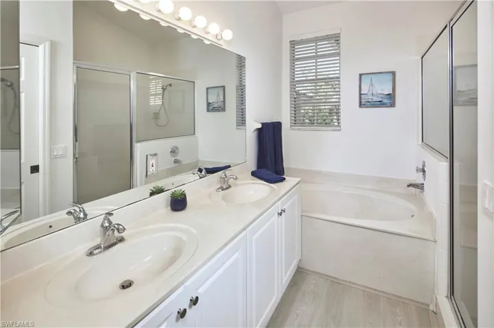 Dual vanities in primary bath with tub and shower combo.
