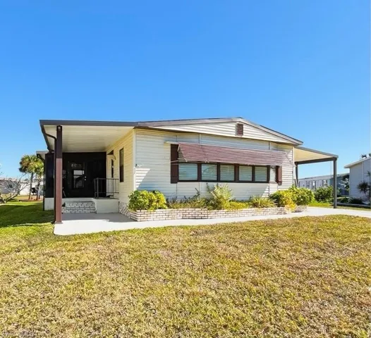 Manufactured / mobile home featuring a front lawn and a carport