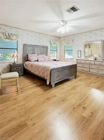 Bedroom featuring a textured ceiling, light wood-style floors, and ceiling fan
