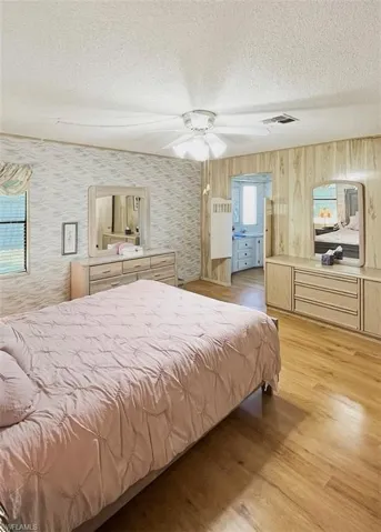 Bedroom featuring a textured ceiling, light wood-type flooring, and a ceiling fan