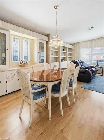 Dining area with wood walls, light wood finished floors, and a textured ceiling