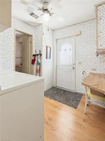 Entrance foyer featuring a textured ceiling, washer / clothes dryer, light wood-style floors, and ceiling fan