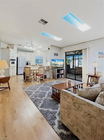 Living room featuring wallpapered walls, light wood-style flooring, and ceiling fan