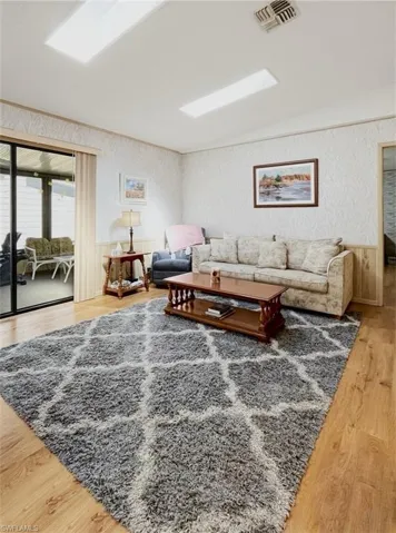 Living area featuring a wainscoted wall, light wood-type flooring, and wallpapered walls