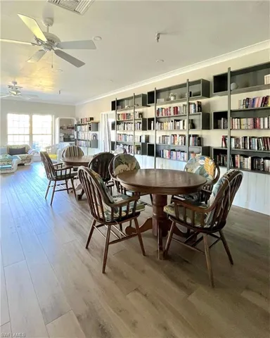 Dining area with wood finished floors, ornamental molding, and a ceiling fan