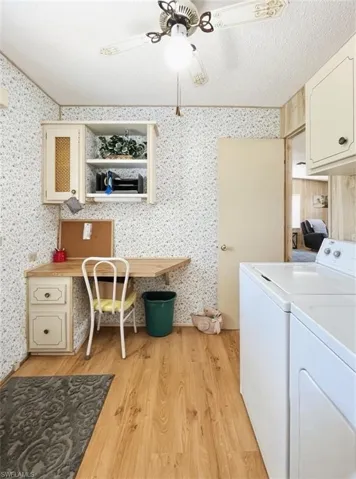 Laundry area featuring a textured ceiling, light wood-type flooring, an office area, washing machine and clothes dryer, and cabinet space
