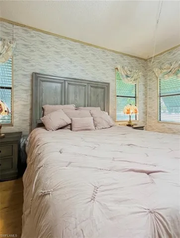 Bedroom with a textured ceiling, wallpapered walls, and ornamental molding